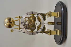 Late 19th / early 20th Century Gothic skeleton clock, the silvered chapter ring with Roman numerals, the two train fusee movement striking on a bell, mounted to an oval ebonised plinth base with glass